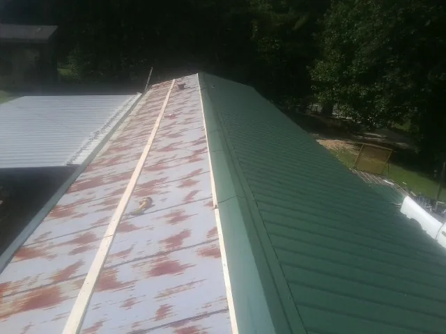Old rusted panels beside newly installed green metal roofing — Wind Damage Roof Repair by Roofing Brothers in Monmouth