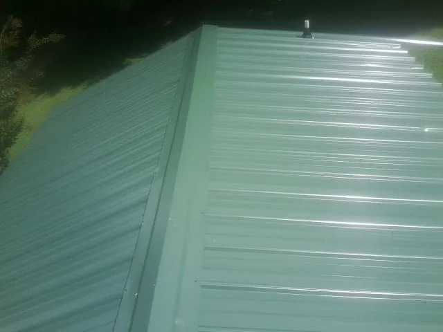New green metal panels meeting at the ridge of a roof — Flat Roof Repair work by our crew in Monmouth