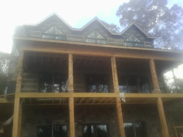 Dormers and porch framing on a large log home under construction — Roof Coating work by our crew in Monmouth